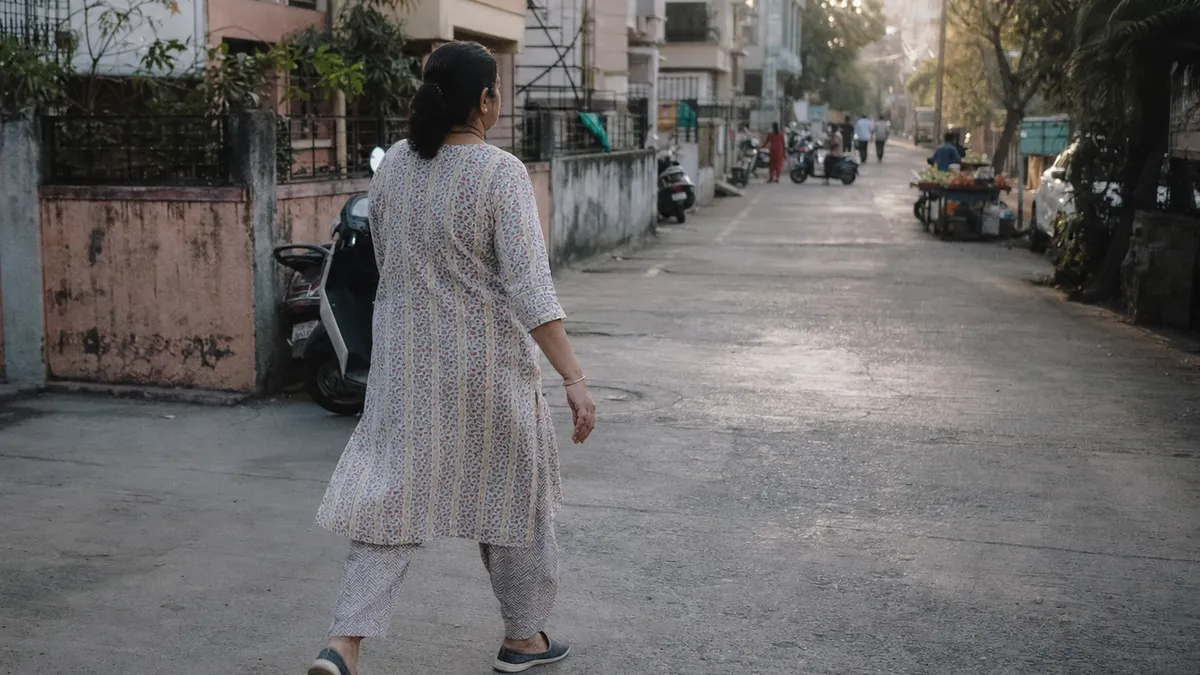 A woman walking on an ordinary residential street in urban India early in the morning