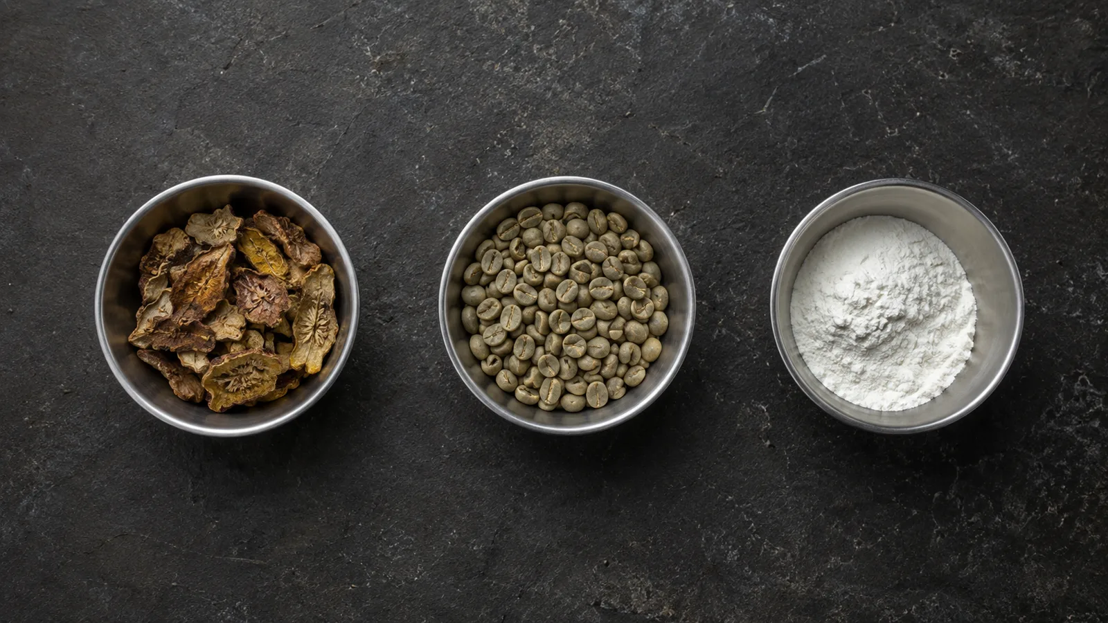 Three small steel bowls holding dried garcinia rind, green coffee beans and a white powder