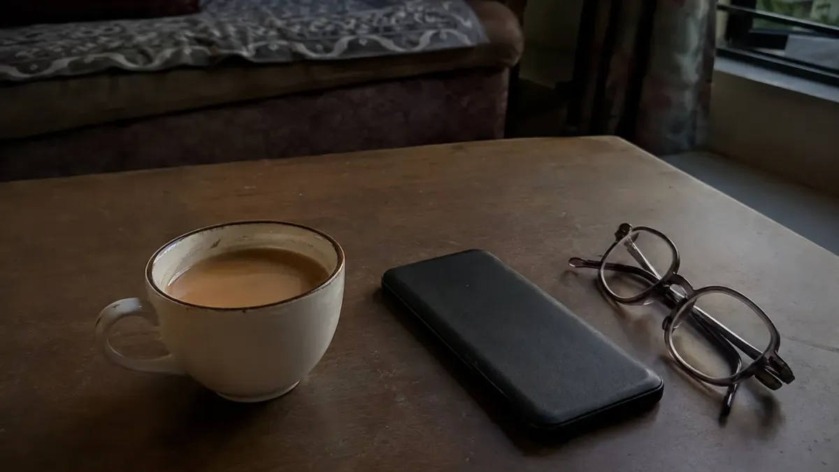 A cup of tea gone cold on a low table beside a phone lying face down